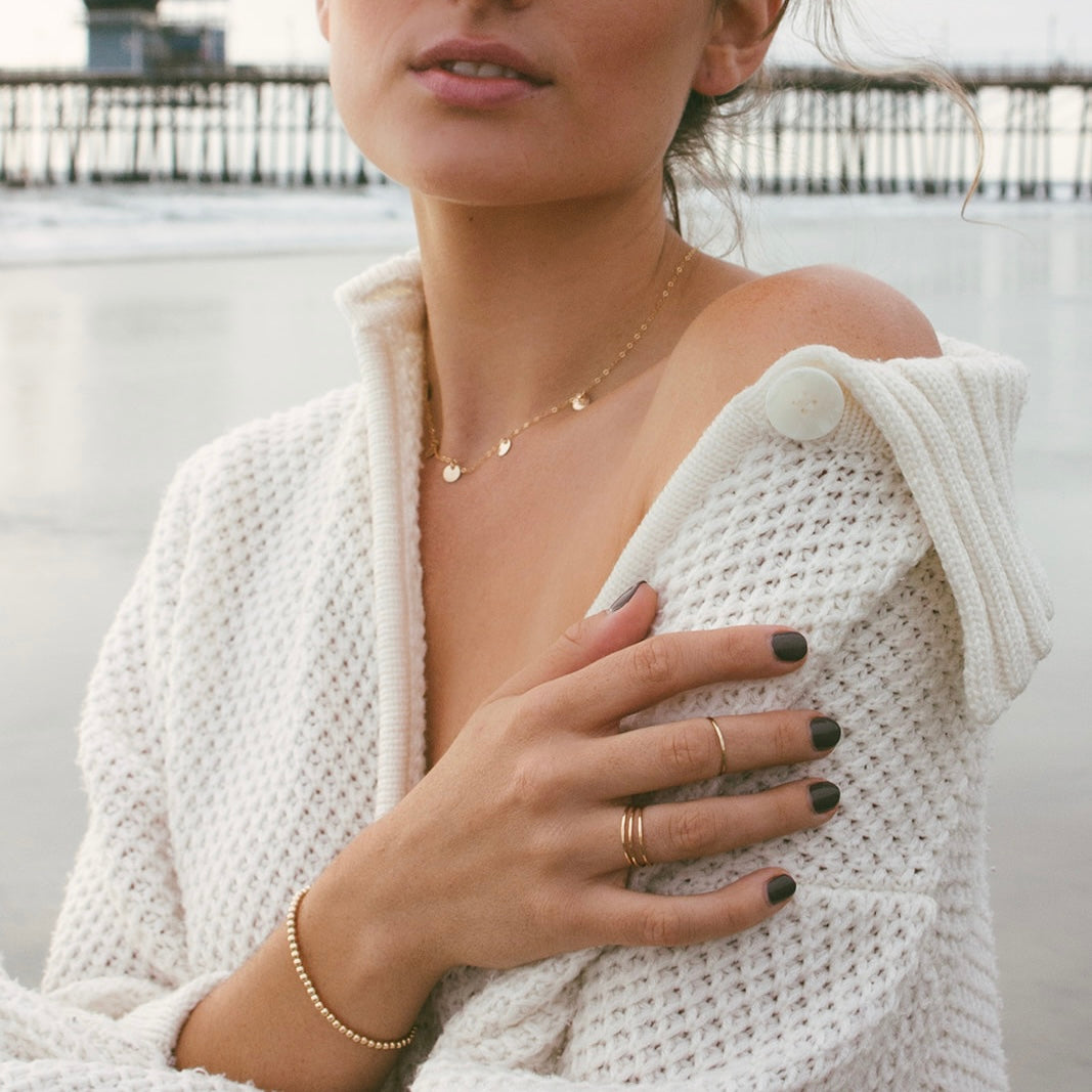 Teressa Lane Jewelry handmade stacking ring set worn on female hand with dark nail polish and white sweater