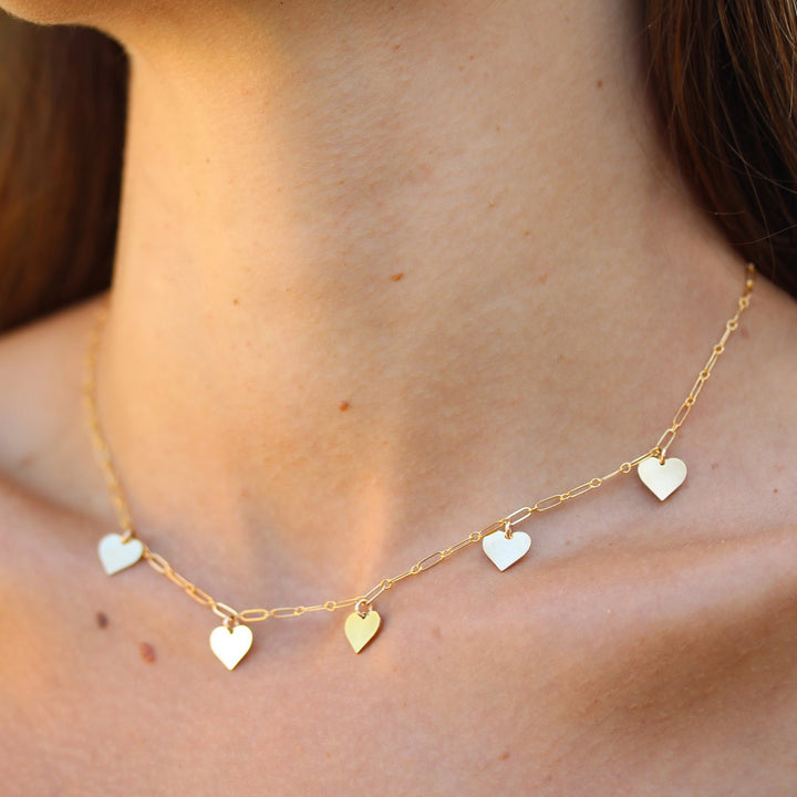 Close-up of the Heart necklace at the base of the neck, five gold filled hearts spaced along a fine chain