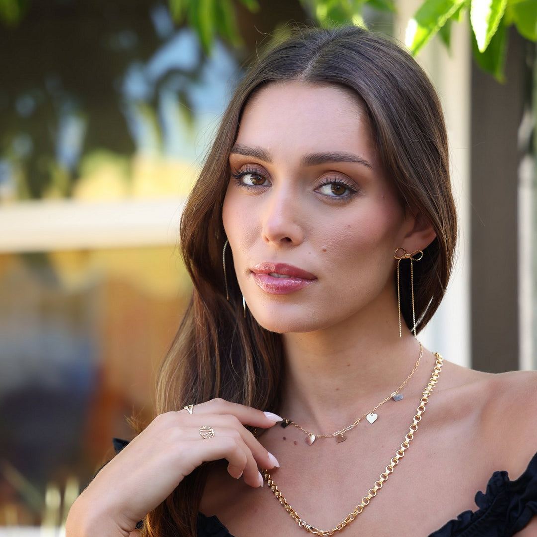 Model in an off-the-shoulder black top wearing the Heart necklace layered with the Vivienne necklace