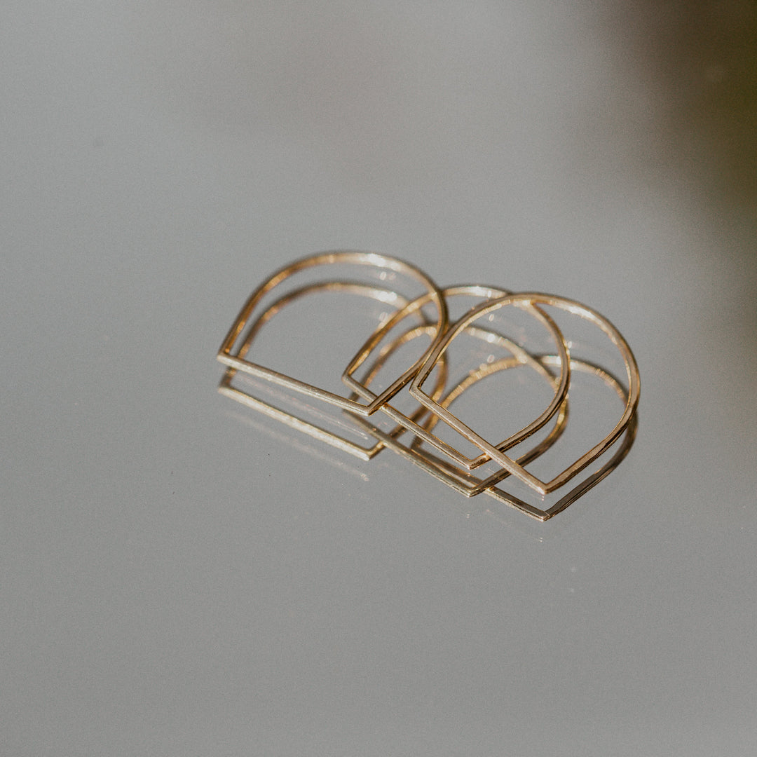 Gold hand shaped Remi ring on a light gray background