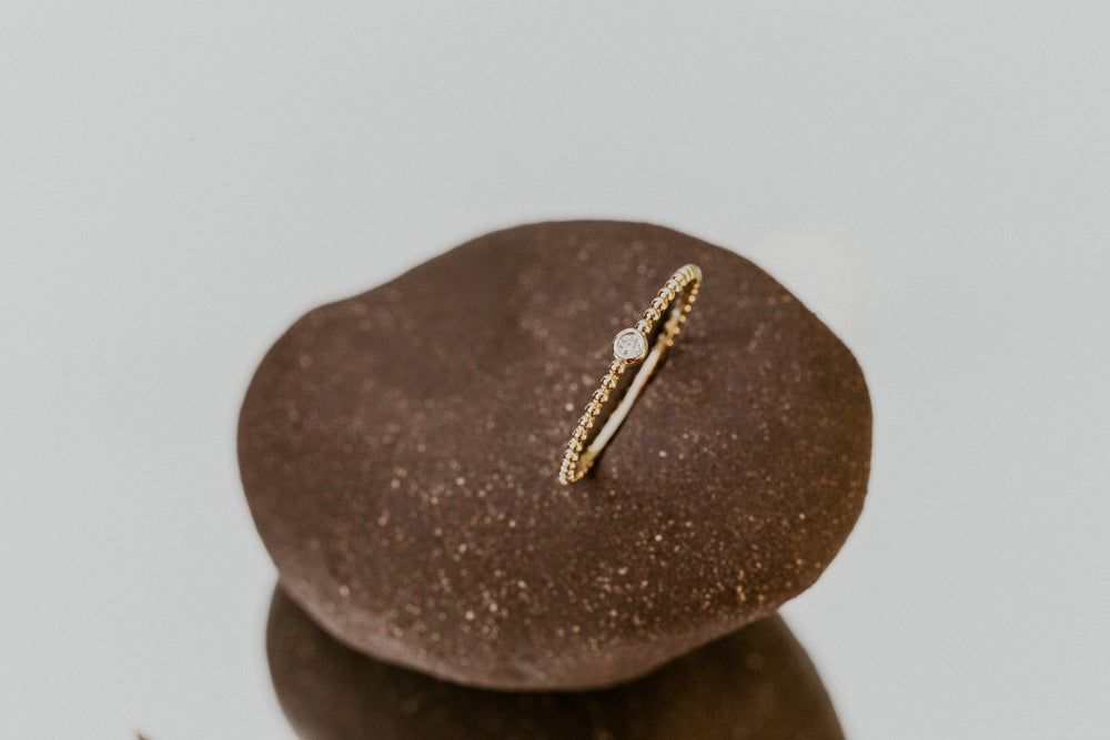 14k Gold ring with a diamond on a brown stone against a light gray background
