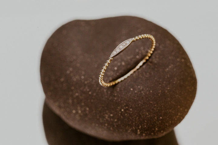 14k Gold ring with a diamonds in an oval design on a brown stone surface