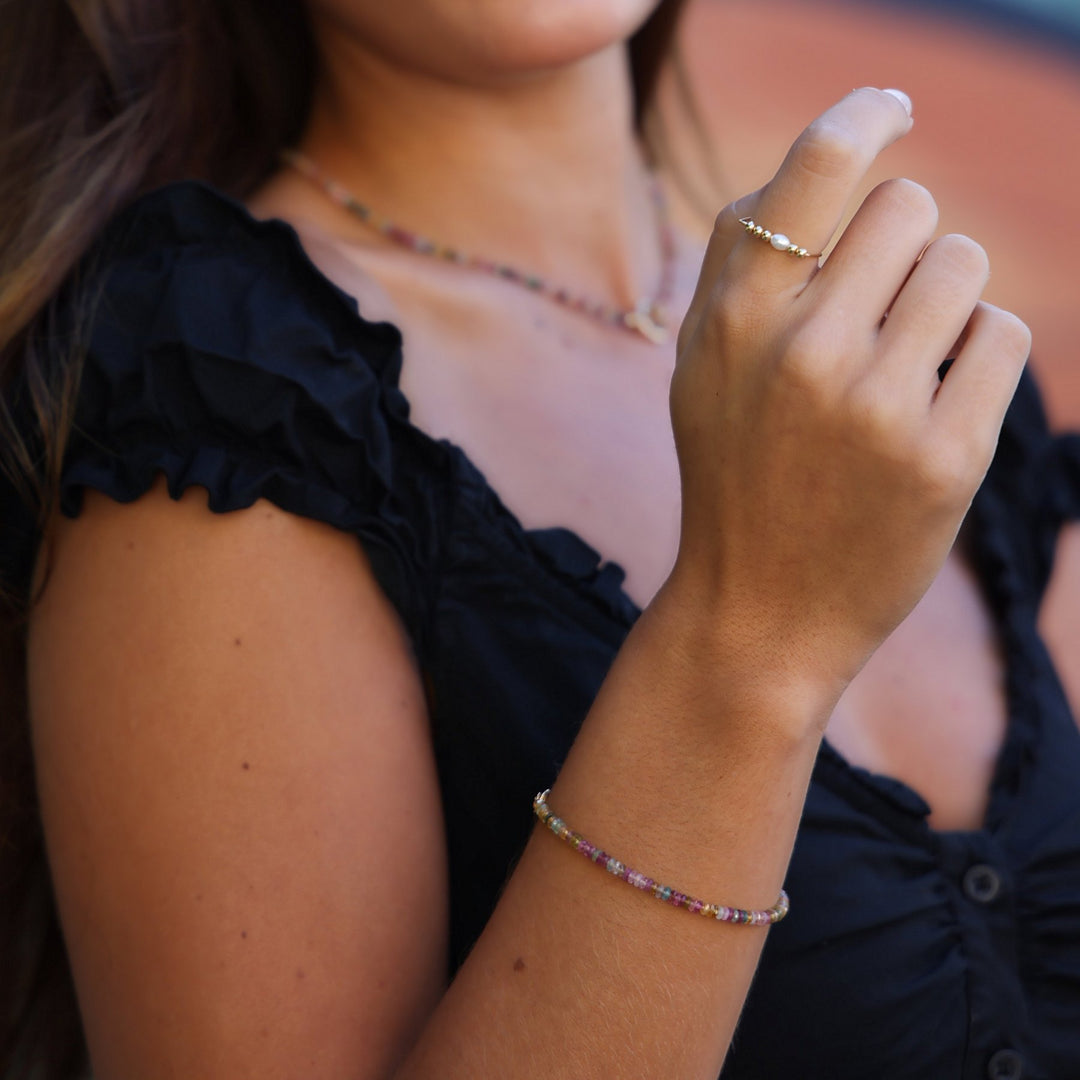 Close-up of the Joy tourmaline beaded bracelet on the wrist with a gold and pearl ring