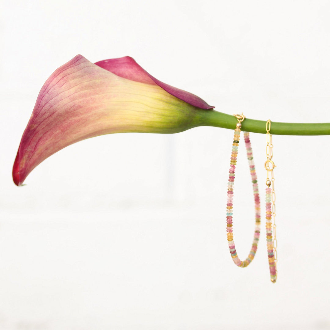 Beaded and chain Joy bracelets hanging from a pink calla lily stem