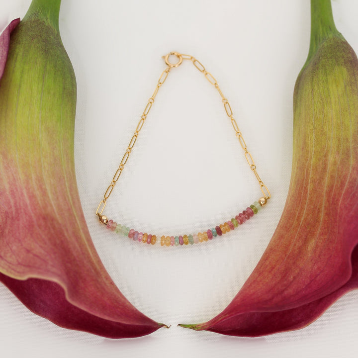 Chain style Joy bracelet, a bar of tourmaline heishi beads on 14k gold filled paperclip chain, framed by pink calla lilies