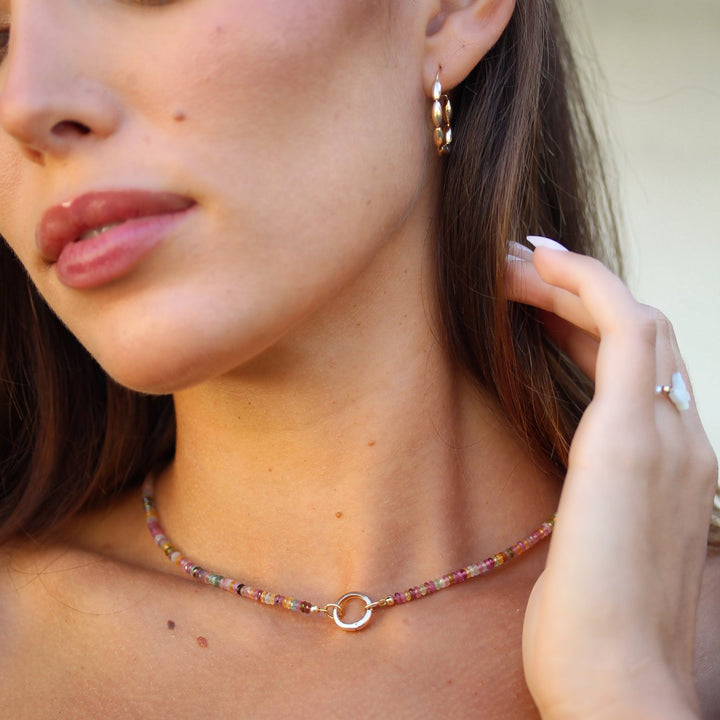 Model looking down wearing the Joy multicolor tourmaline beaded necklace with gold hoop earrings