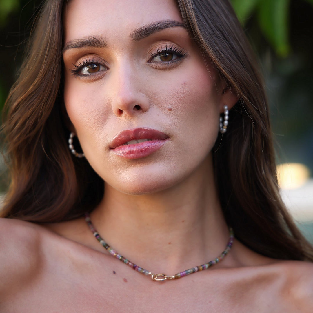 Portrait of a model wearing the Joy tourmaline heishi bead necklace with pearl hoop earrings