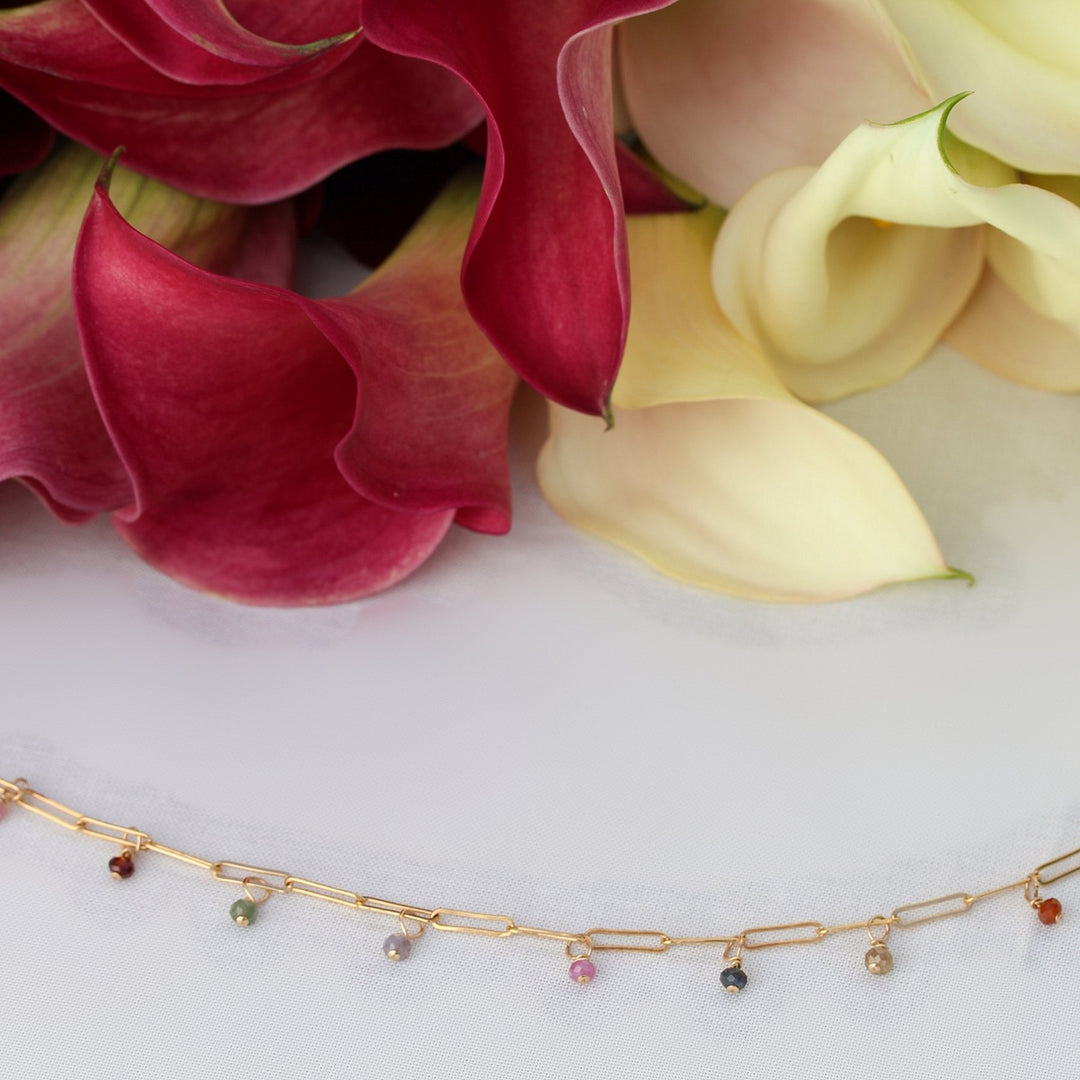 Juliette necklace, faceted multicolored spinel beads dangling from 14k gold filled paperclip chain, in front of calla lilies