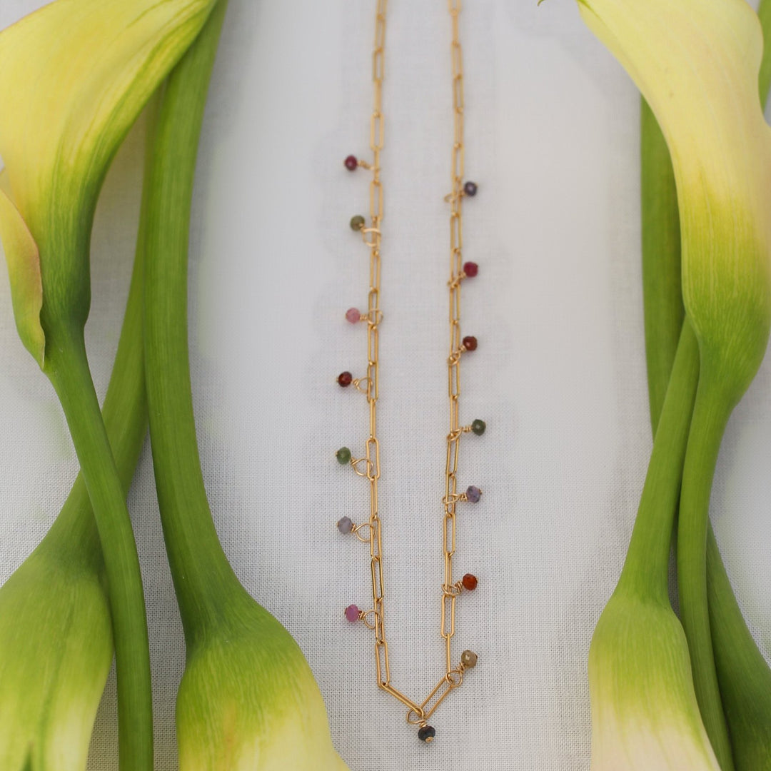 Juliette spinel bead necklace on gold filled paperclip chain laid between cream calla lily stems