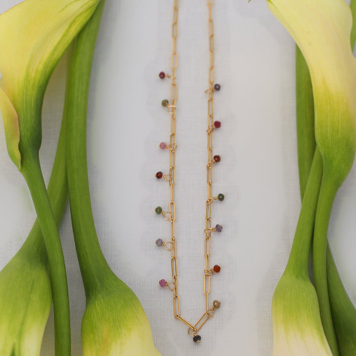 Juliette spinel bead necklace on gold filled paperclip chain laid between cream calla lily stems