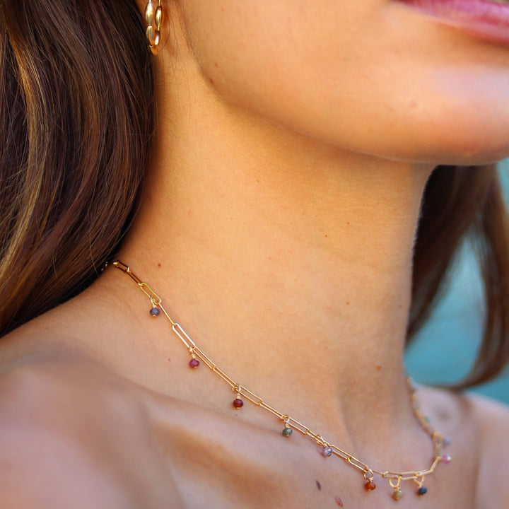 Side view of the Juliette spinel and paperclip chain necklace worn with gold hoop earrings