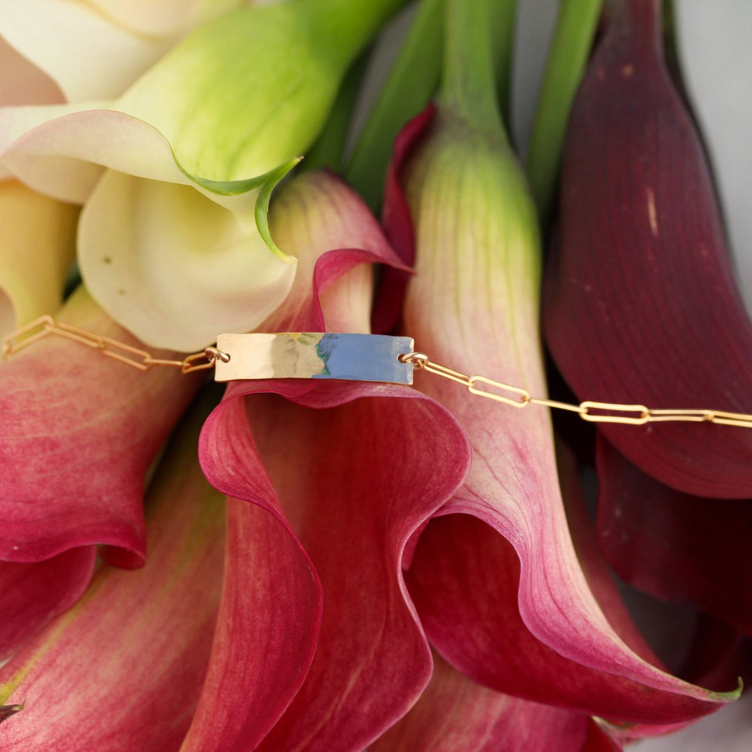 Kim hammered gold filled bar bracelet draped across pink and burgundy calla lilies