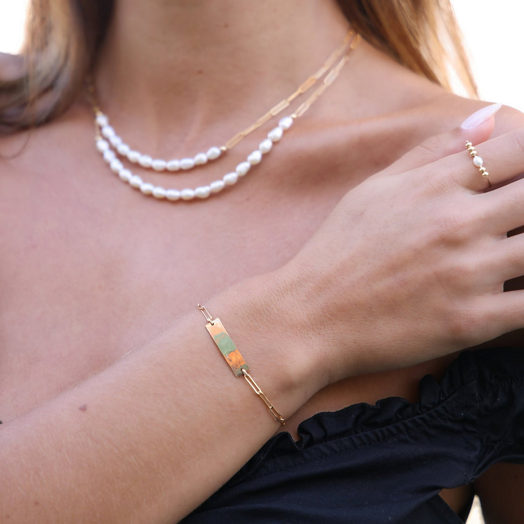 Kim bar bracelet worn on the wrist with the layered Colette pearl necklaces and a gold and pearl ring