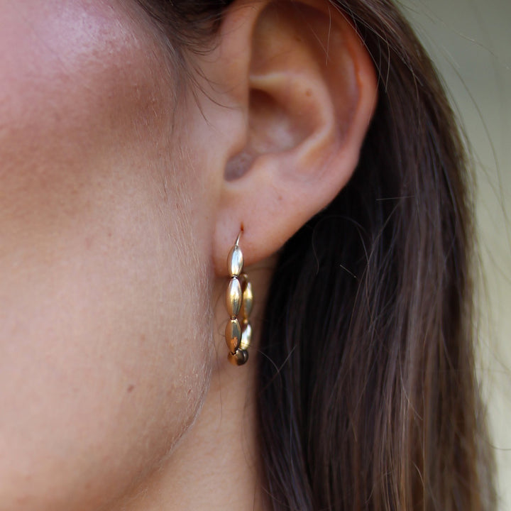 Close-up of the Gold Bead Solace hoop on the ear, polished 14k gold filled oval beads