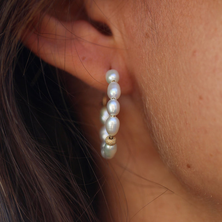 Close-up of the Pearl Solace hoop on the ear, freshwater rice pearls with a sparkling gold bead