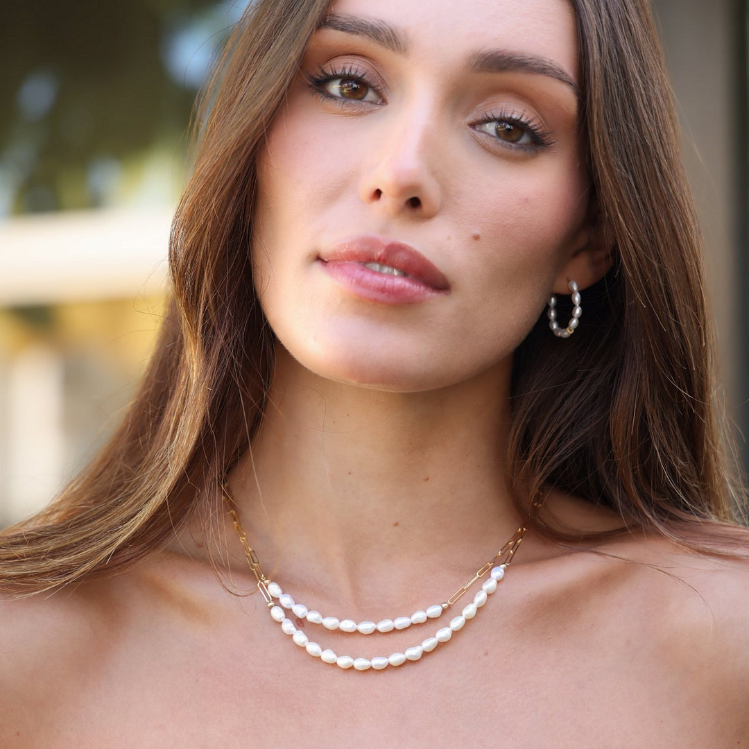 Model wearing Pearl Solace hoops with both Colette pearl necklaces layered