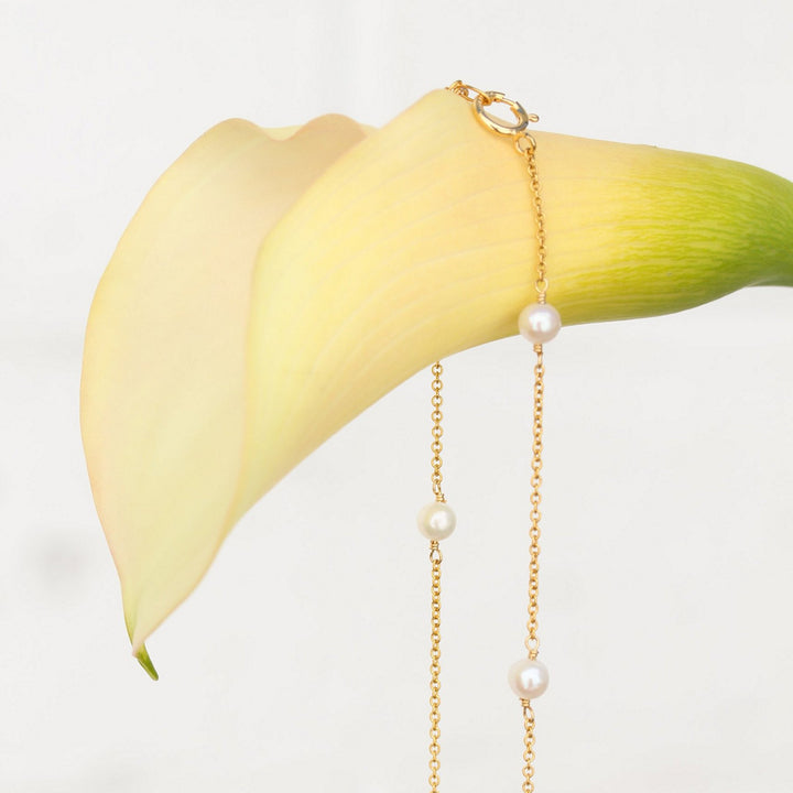 Close-up of the Stella pearl station necklace and its gold filled spring ring clasp on a calla lily
