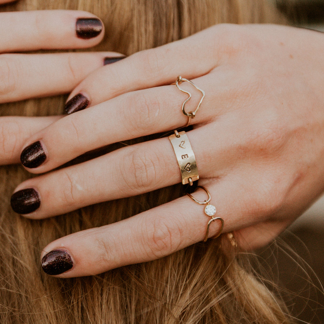Close-up of a hand wearing gold rings with a blurred background