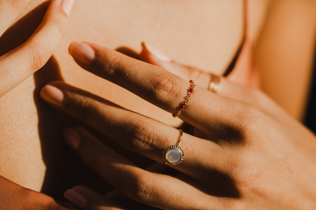 gold chain pink beaded ring on close up of women's hand 