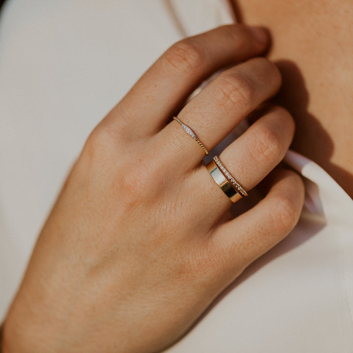Close-up of a hand wearing two gold rings  with diamonds in an oval design on gold band