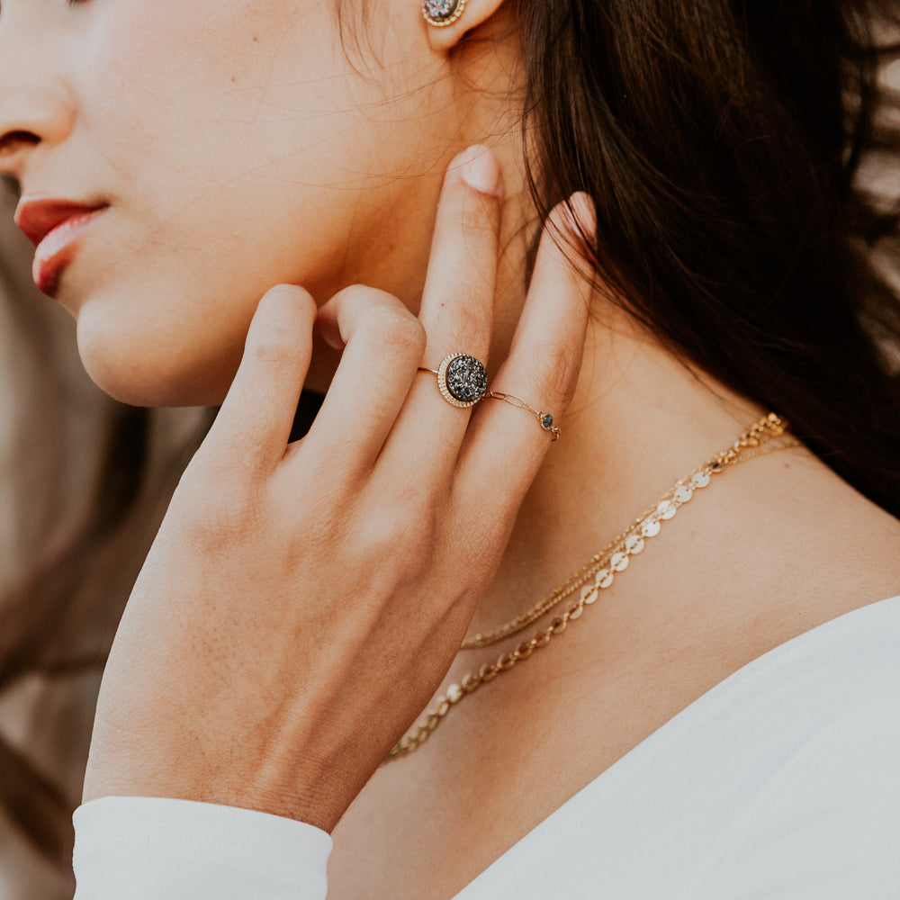 Close-up of a woman wearing black druzy gold rings and necklace.