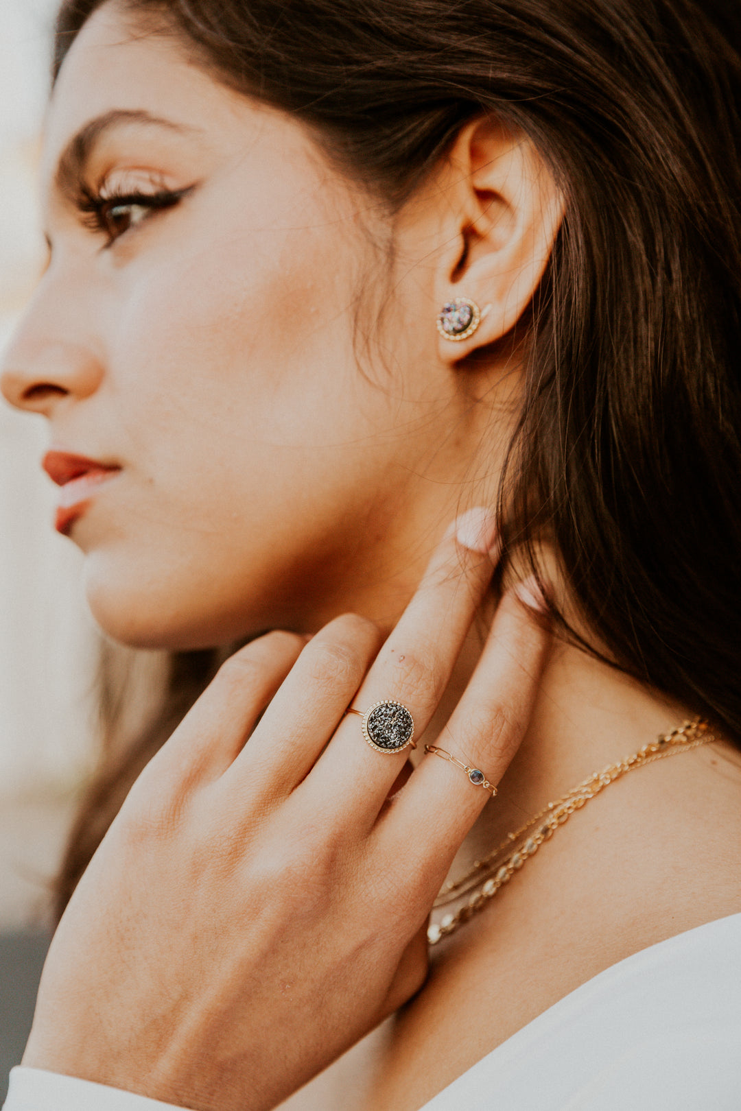 Close-up of a woman wearing a black druzy gold ring with a blurred background