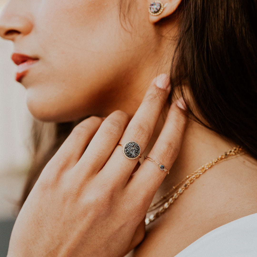 Close-up of a woman wearing black druzy gold rings with a blurred background
