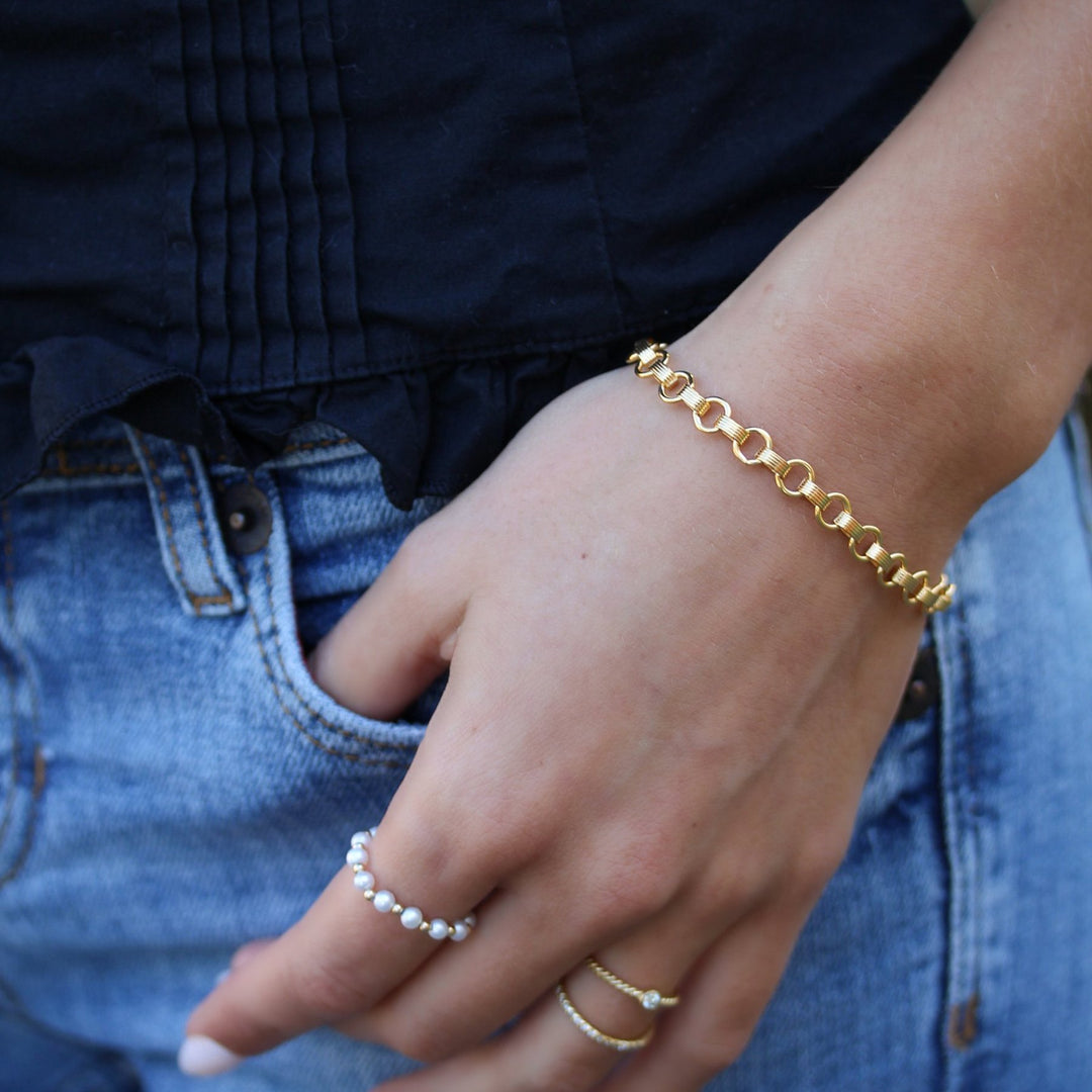 Vivienne bracelet worn on the wrist, round and ribbed 14k gold filled links, with a pearl ring