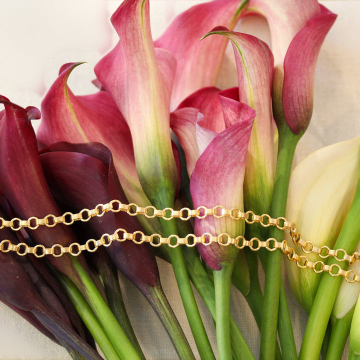 Vivienne gold filled chain necklace draped across burgundy, pink and cream calla lilies