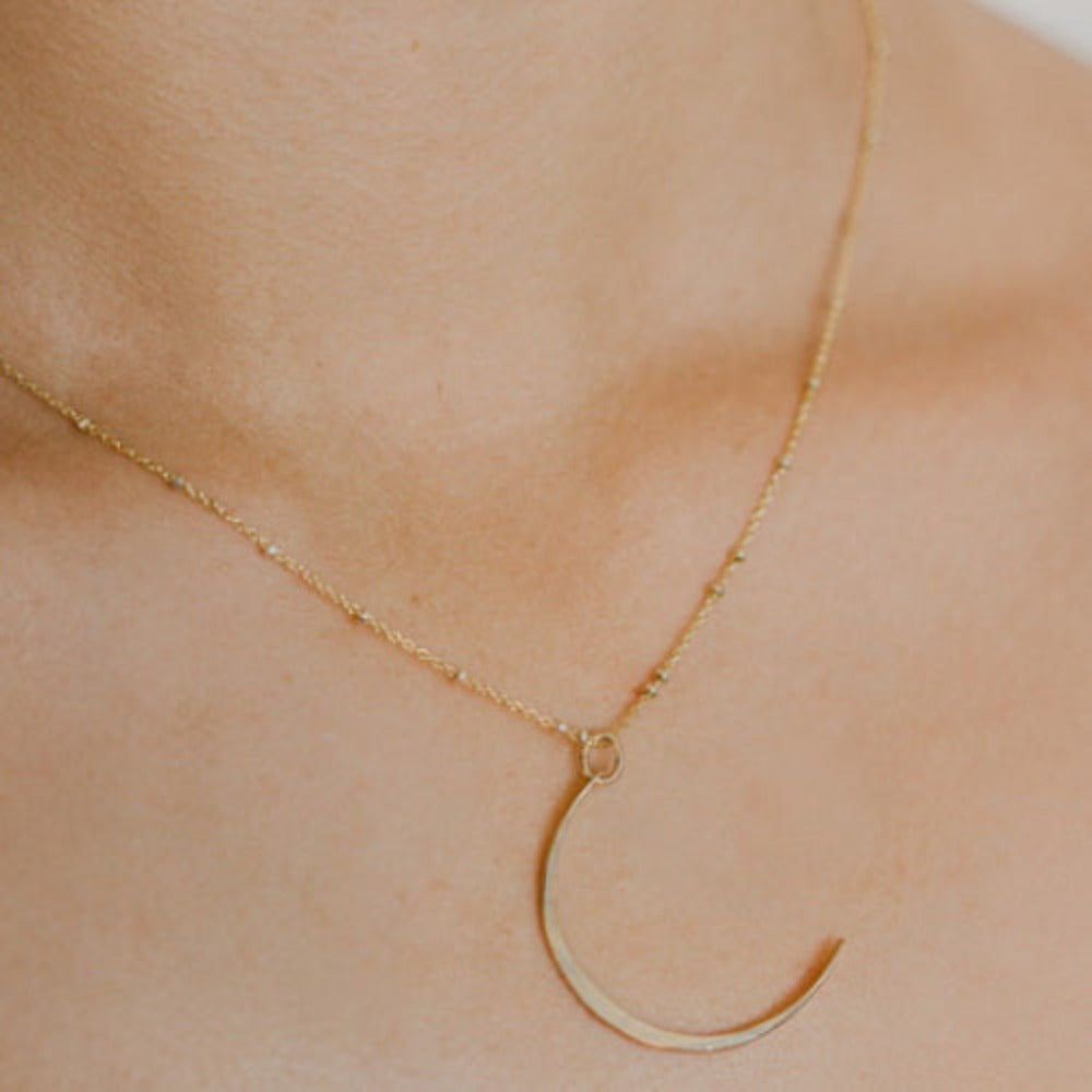 Hand-hammered pendant in the sliver-thin shape of a young moon.