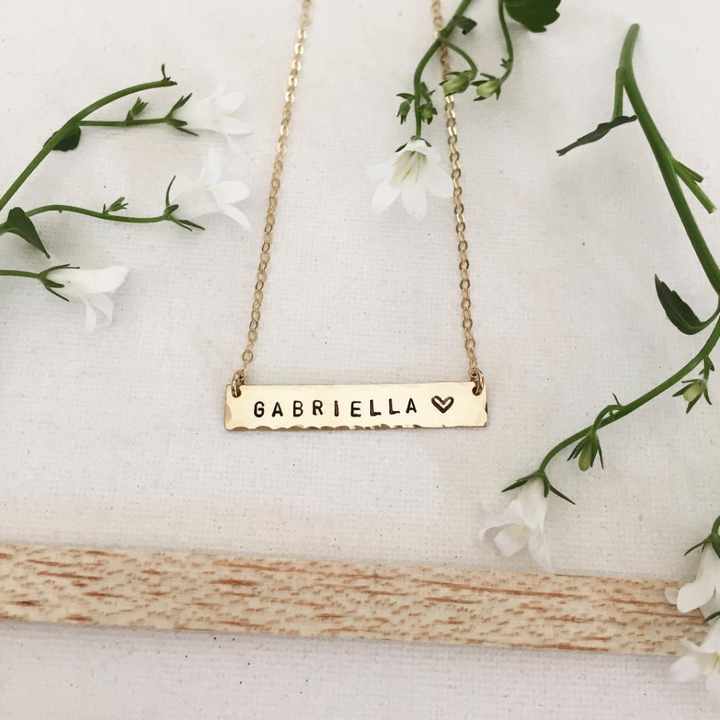 Gold personalized bar necklace from Teressa Lane Jewelry with the name Gabriella and a heart charm